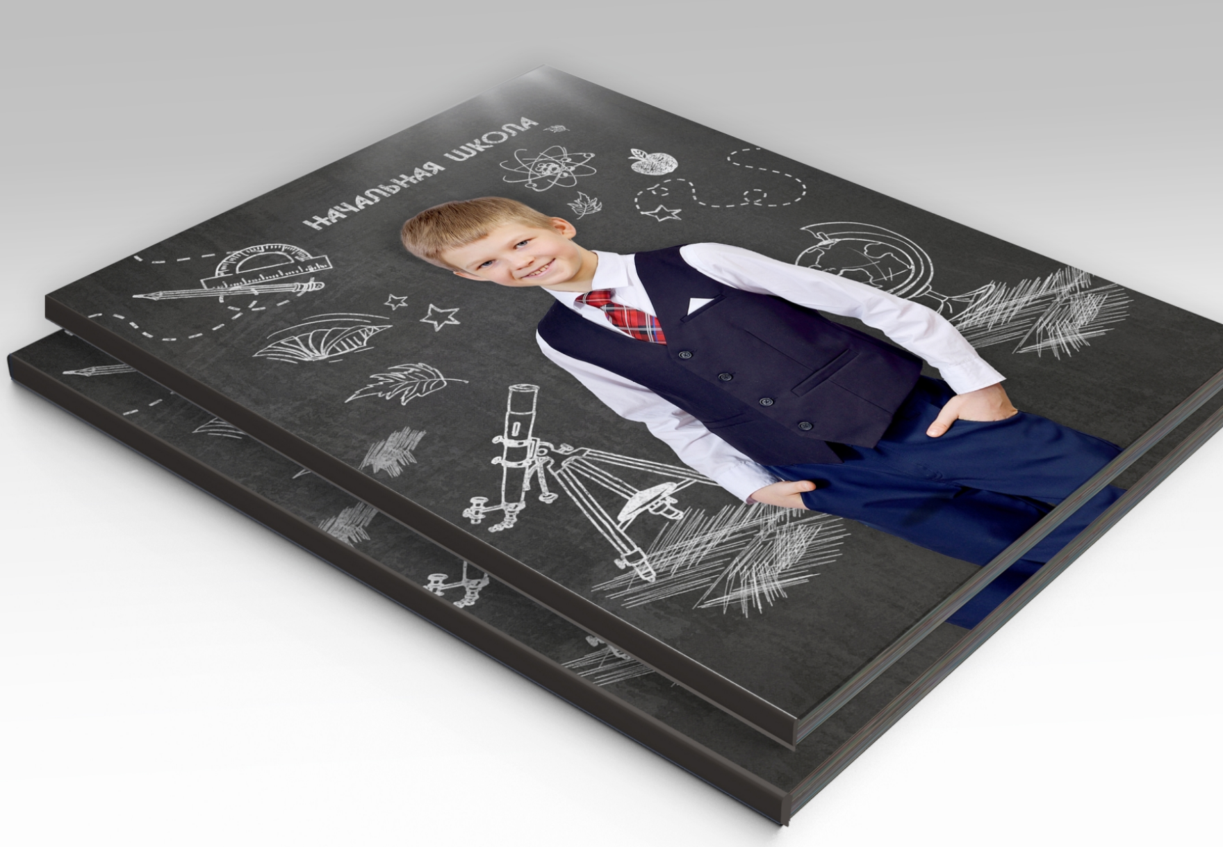 Стопка альбомов выпускника начальной школы, на титульной стороне портрет выпускника.
