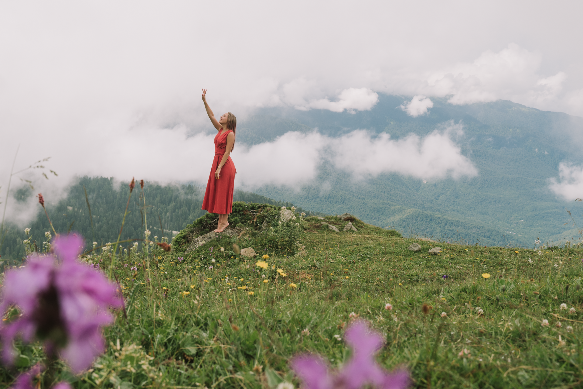 Дальний снимок девушки на фоне горы и облаков 