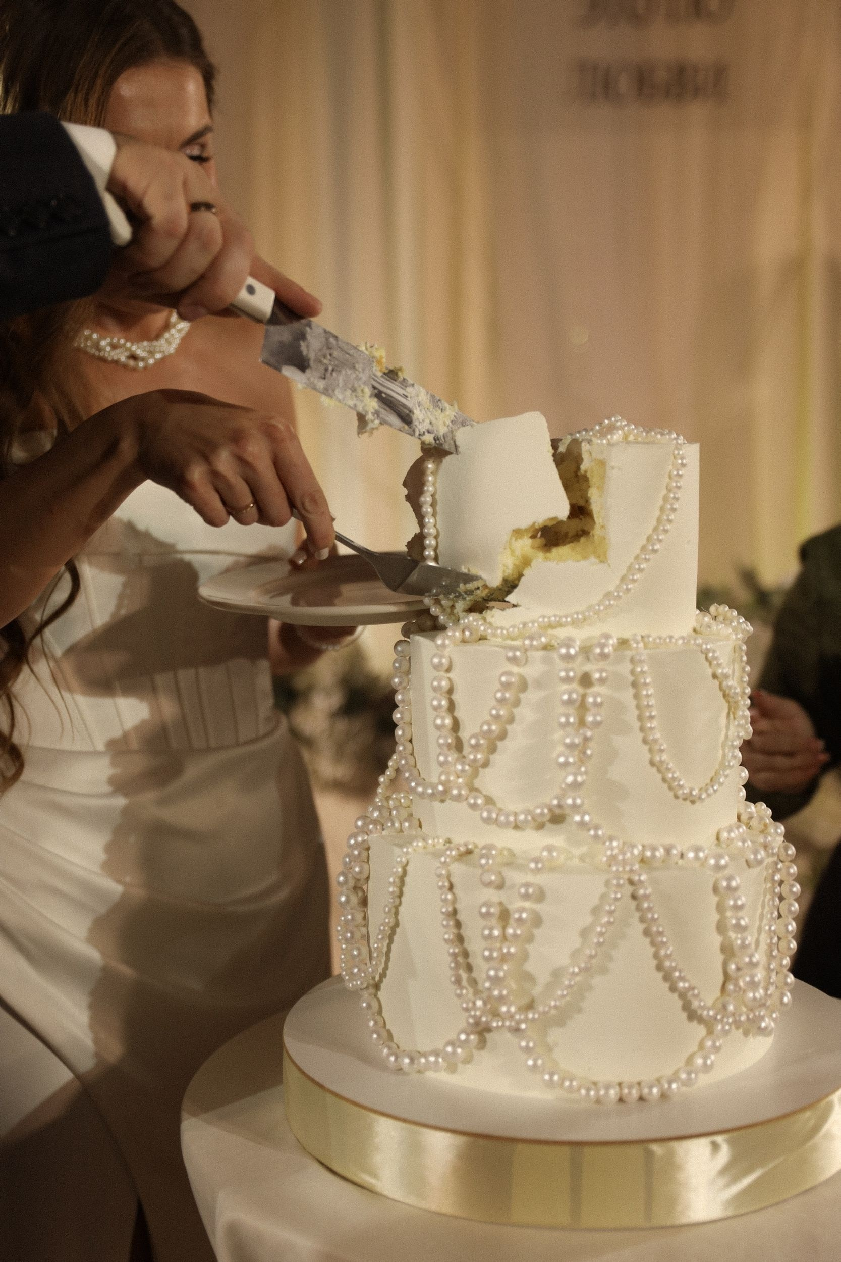 Жених и невеста разрезают свадебный торт на праздничном столе  