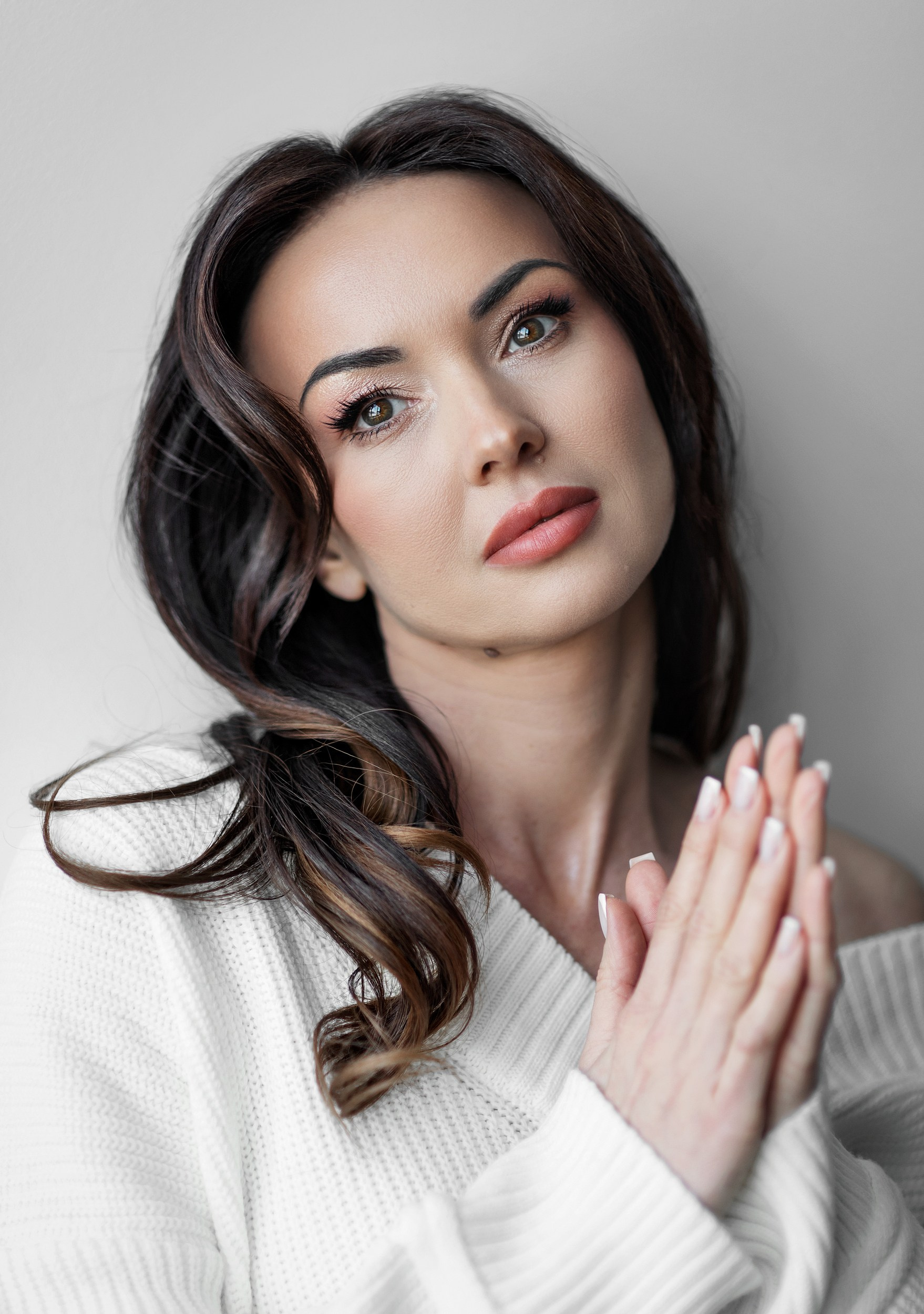 Портрет женщины у стены в белом свитере