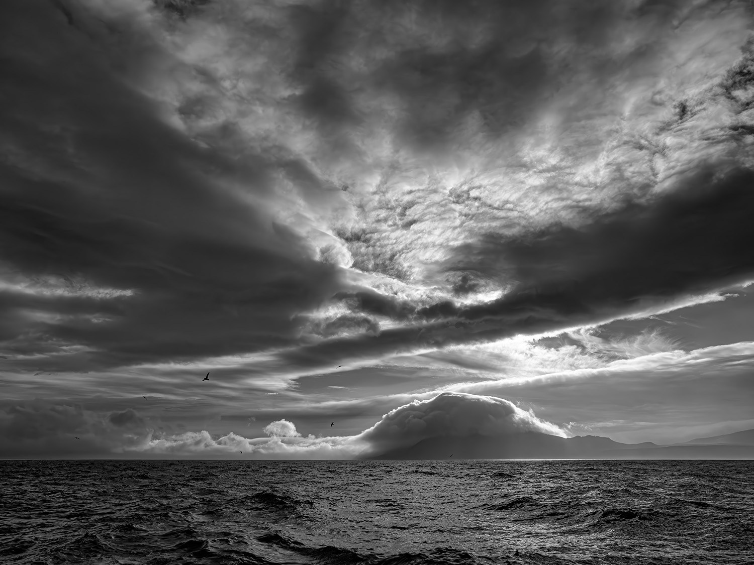 черно-бела фотография Курильского пейзажа на море с драматическим небом и островом "Расшуа" вдалеке