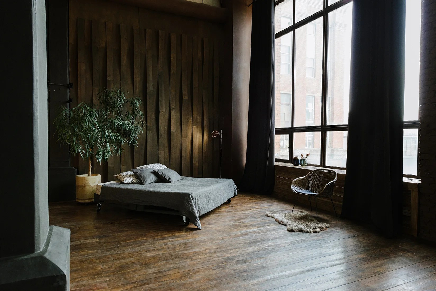большое окно и двуспальная кровать на деревянном полу в студии