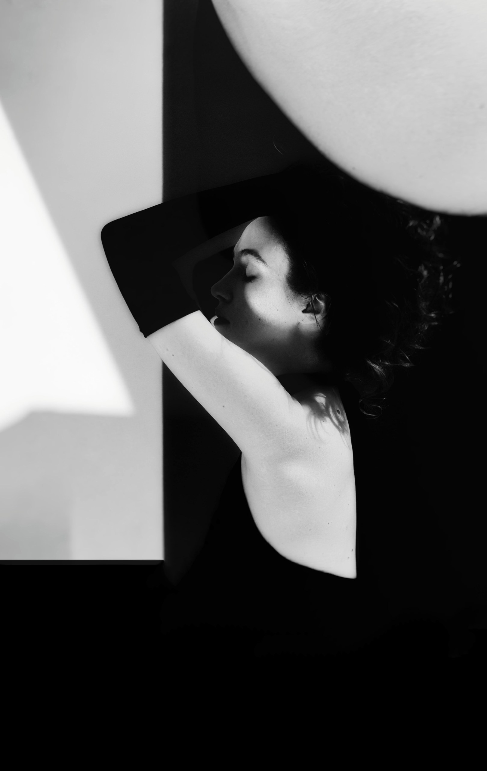 Черно-белое арт-фото с геометрическими формами: профиль девушки, круг и треугольник, минималистичная композиция, игра света