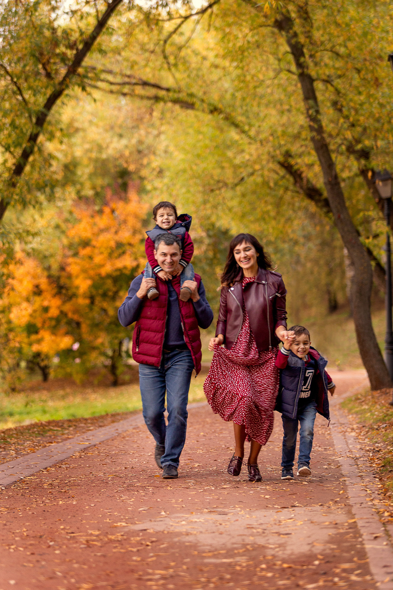 Семья бежит по дорожке осенью счастливые улыбаются.
