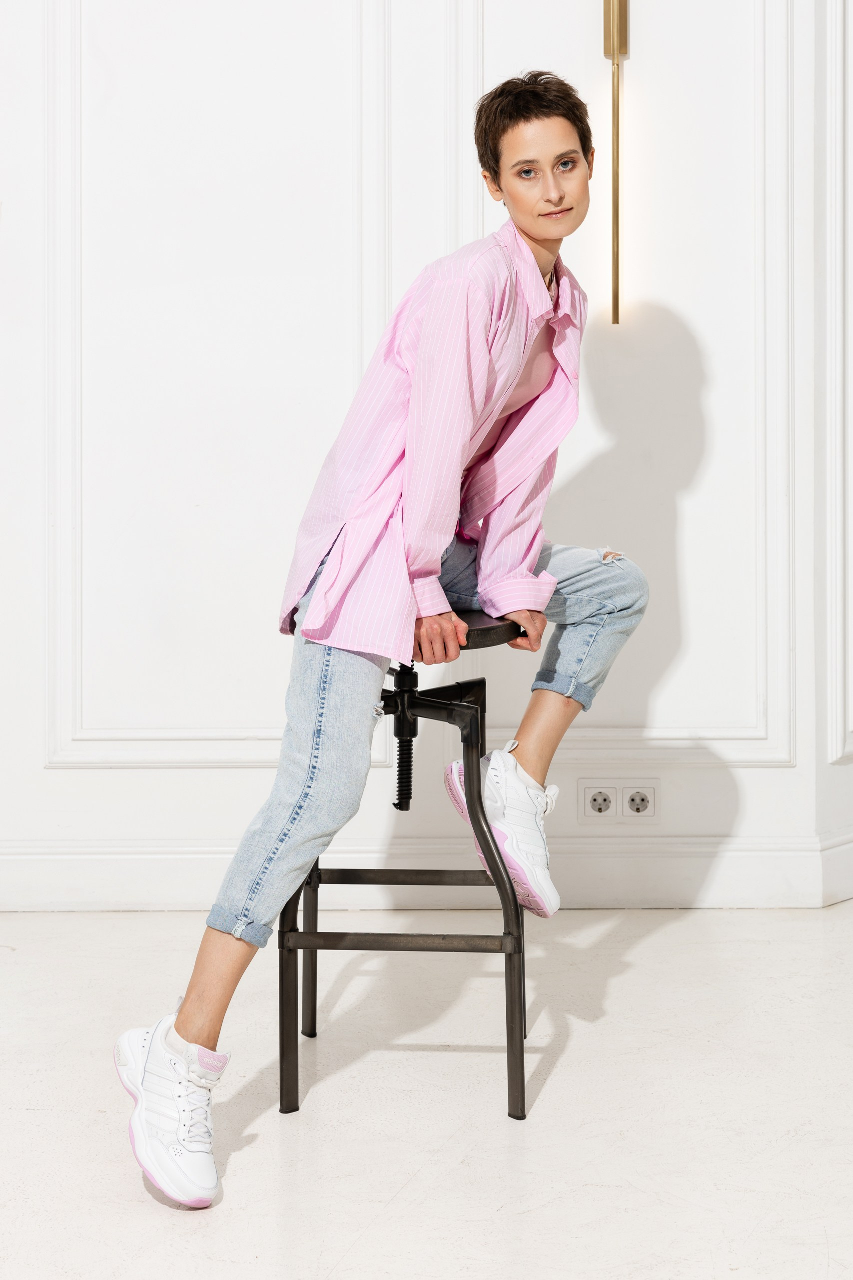 Девушка позирует фотографу на высоком стуле в студии на час