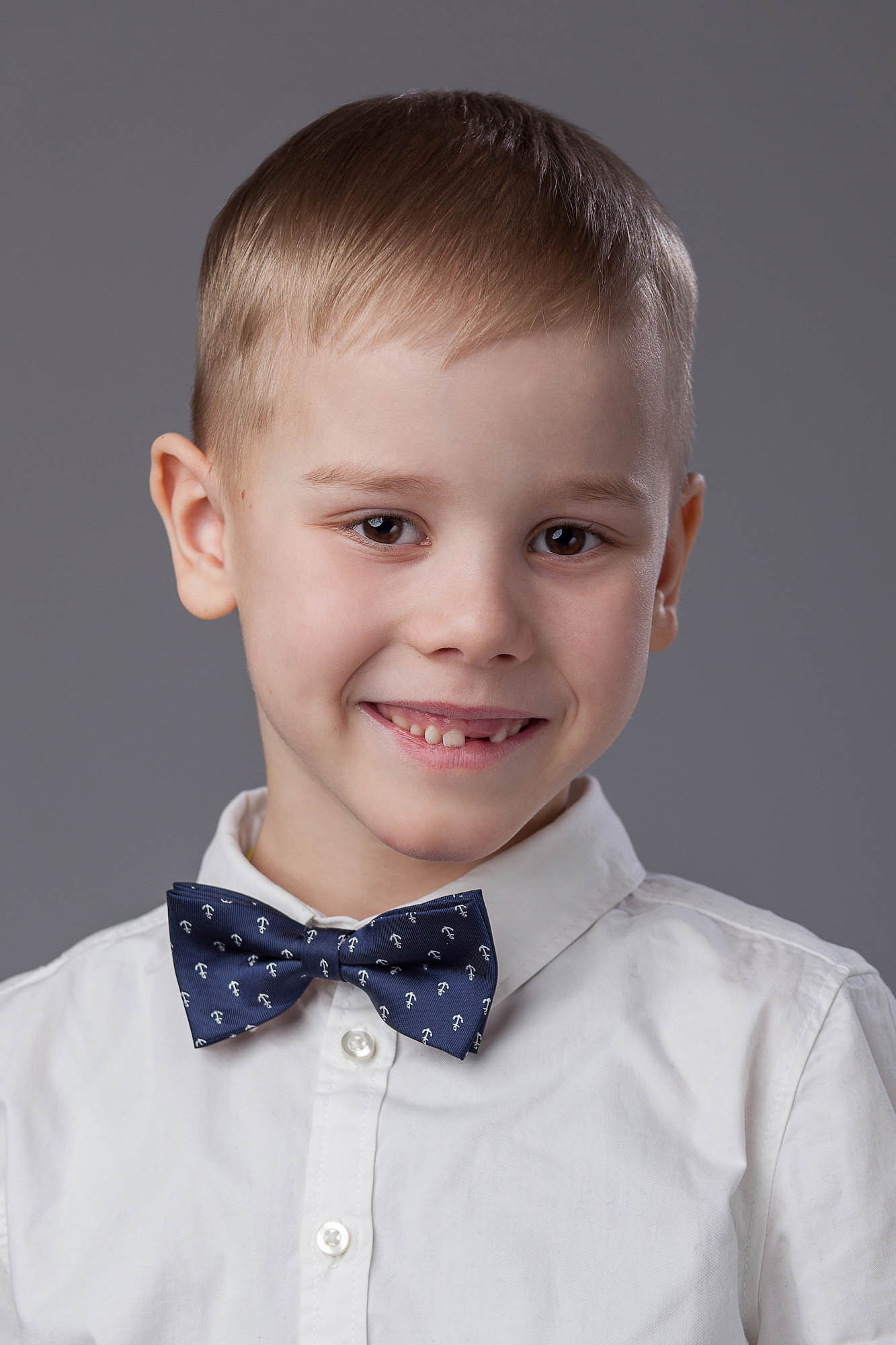 Студийный портрет выпускника детского сада на сером фоне