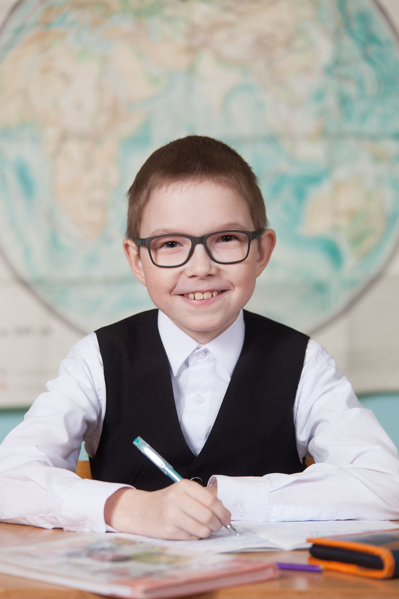 Портрет выпускника  4 класса сидя за партой на фоне карты