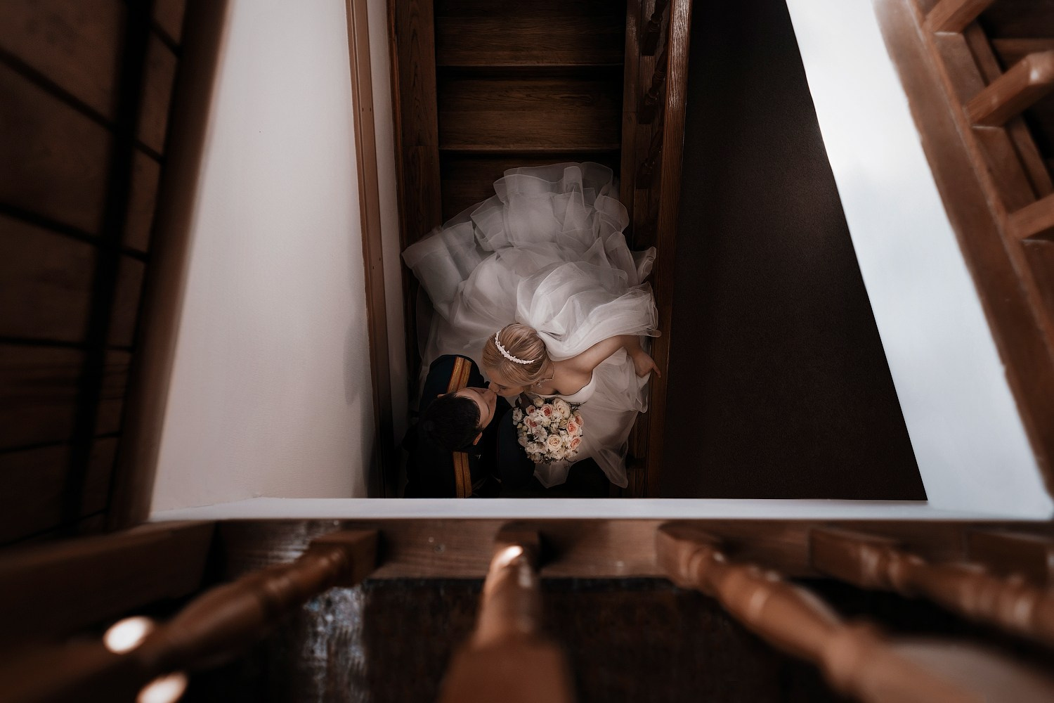 Жених в военной форме и невеста стоят на лестнице и целуются