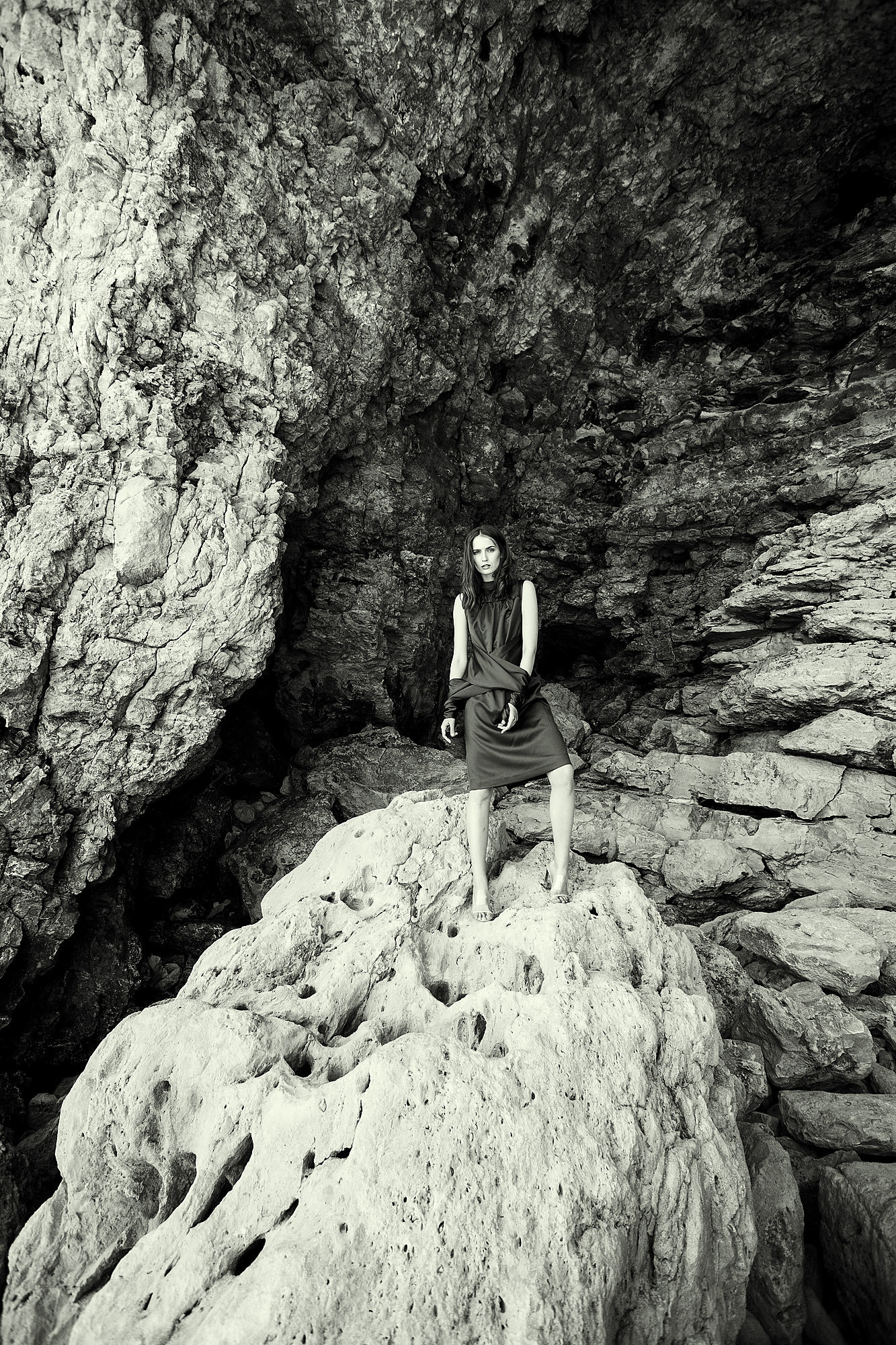 The model stands against the background of rocks in a beautiful dress