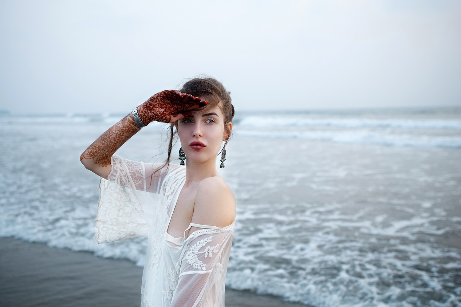 Невеста в элегантном свадебном платье стоит на берегу Финского залива, задумчиво глядя на жениха. Вода спокойная, отражает мягкий свет, вокруг — живописные пейзажи с хвойными деревьями и скалами. Романтическая атмосфера заката или рассвета подчеркивает эмоциональный момент.