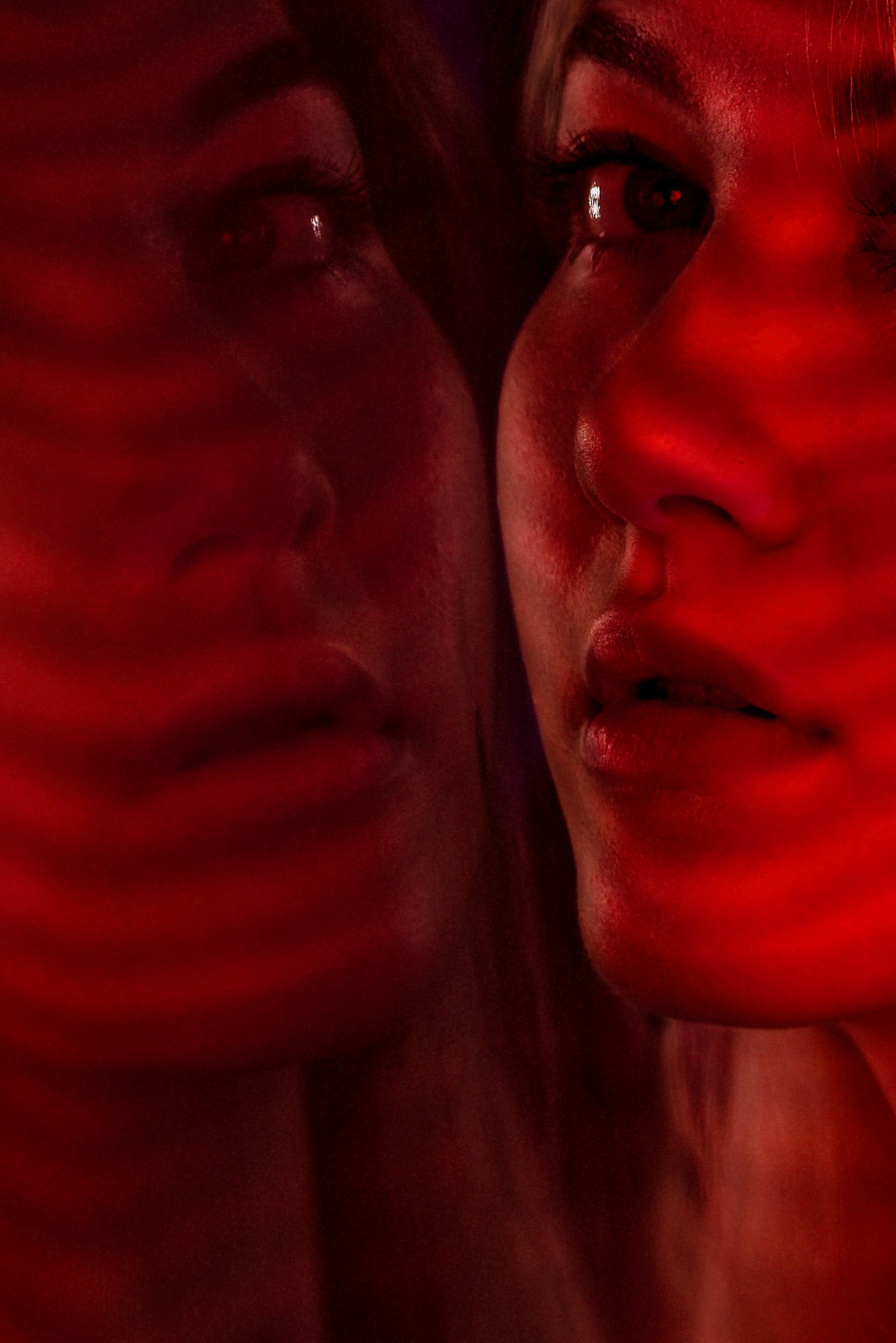 Интимный крупный план двух лиц в красном свете, драматичное освещение, отражение, эмоциональный арт-портрет
