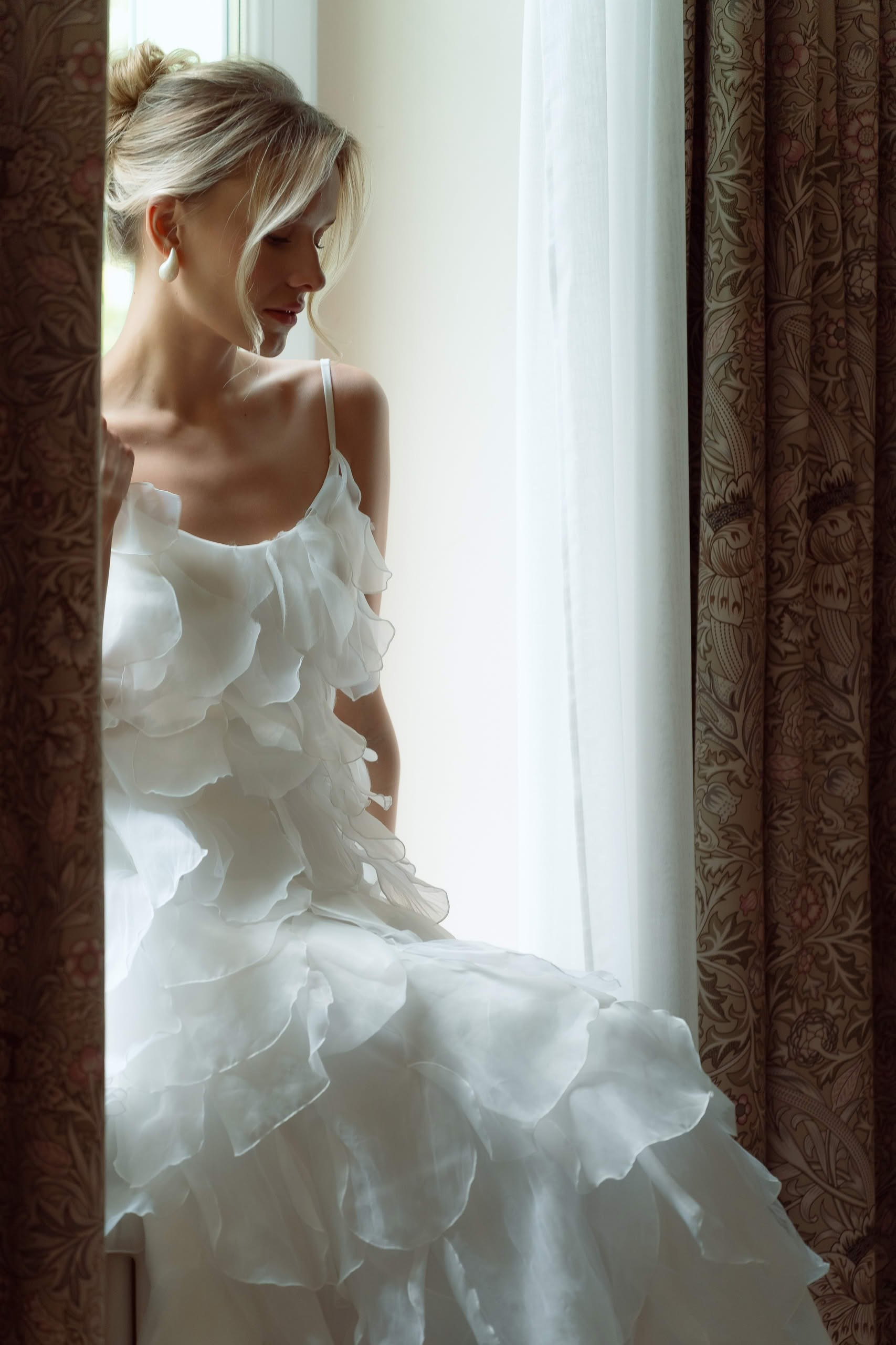 утро невесты невеста в платье у окна естественный свет подготовка к свадьбе