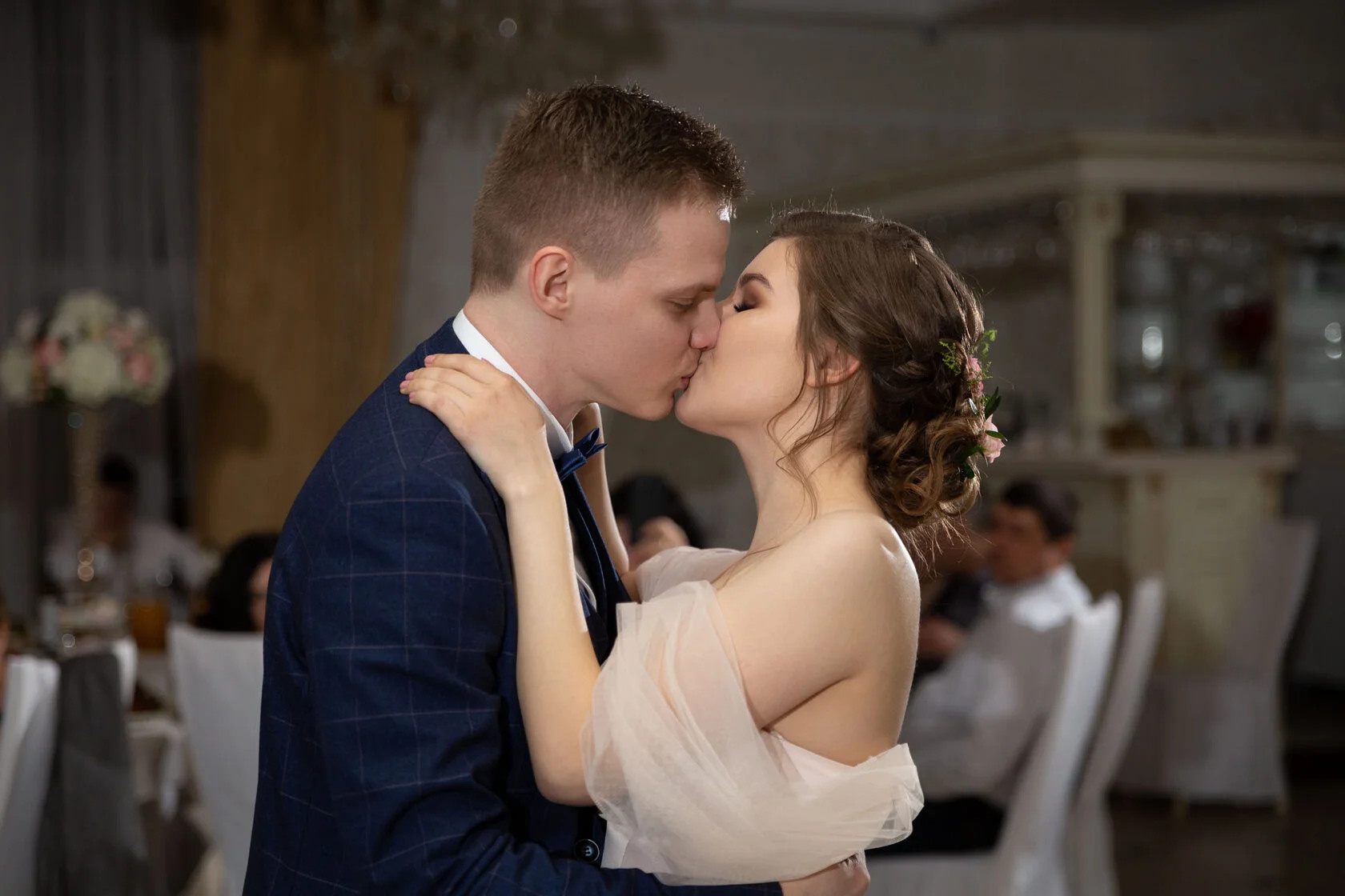 Молодожены целуются на свадебном банкете