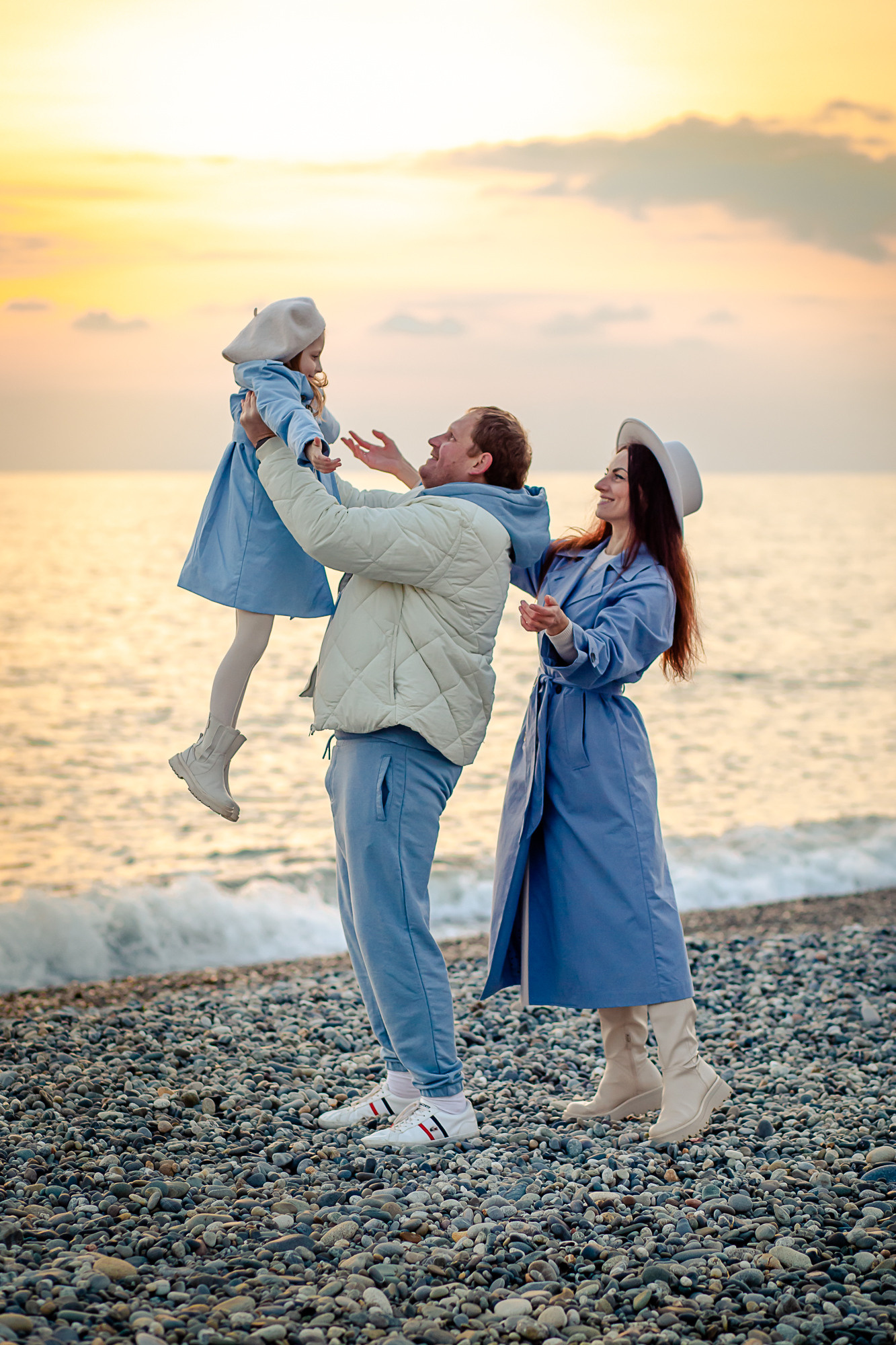 Красивая семья гуляет вечером на закате возле моря