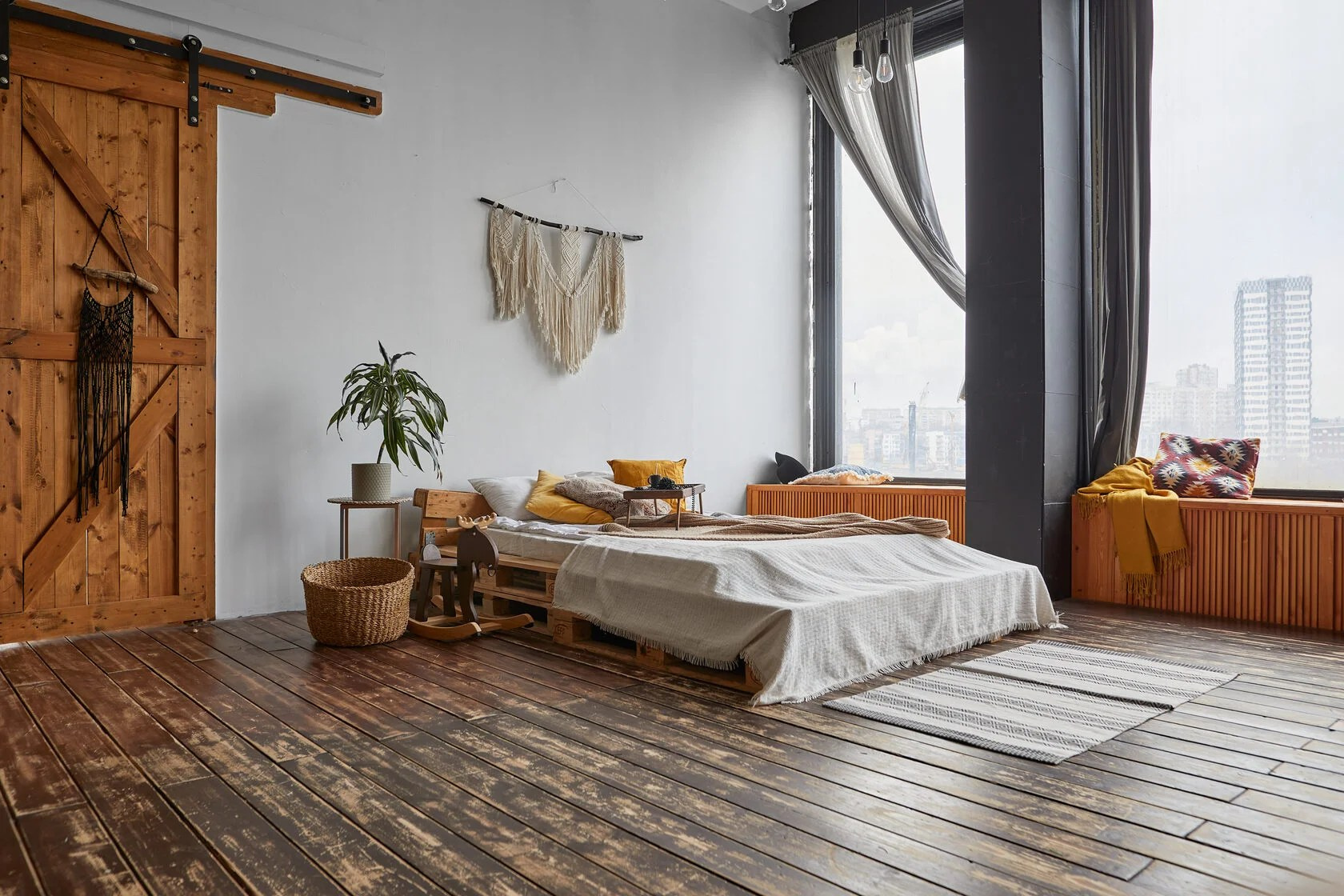 кровать у большого окна сделанная из деревянных палет, деревянная раздвижная дверь